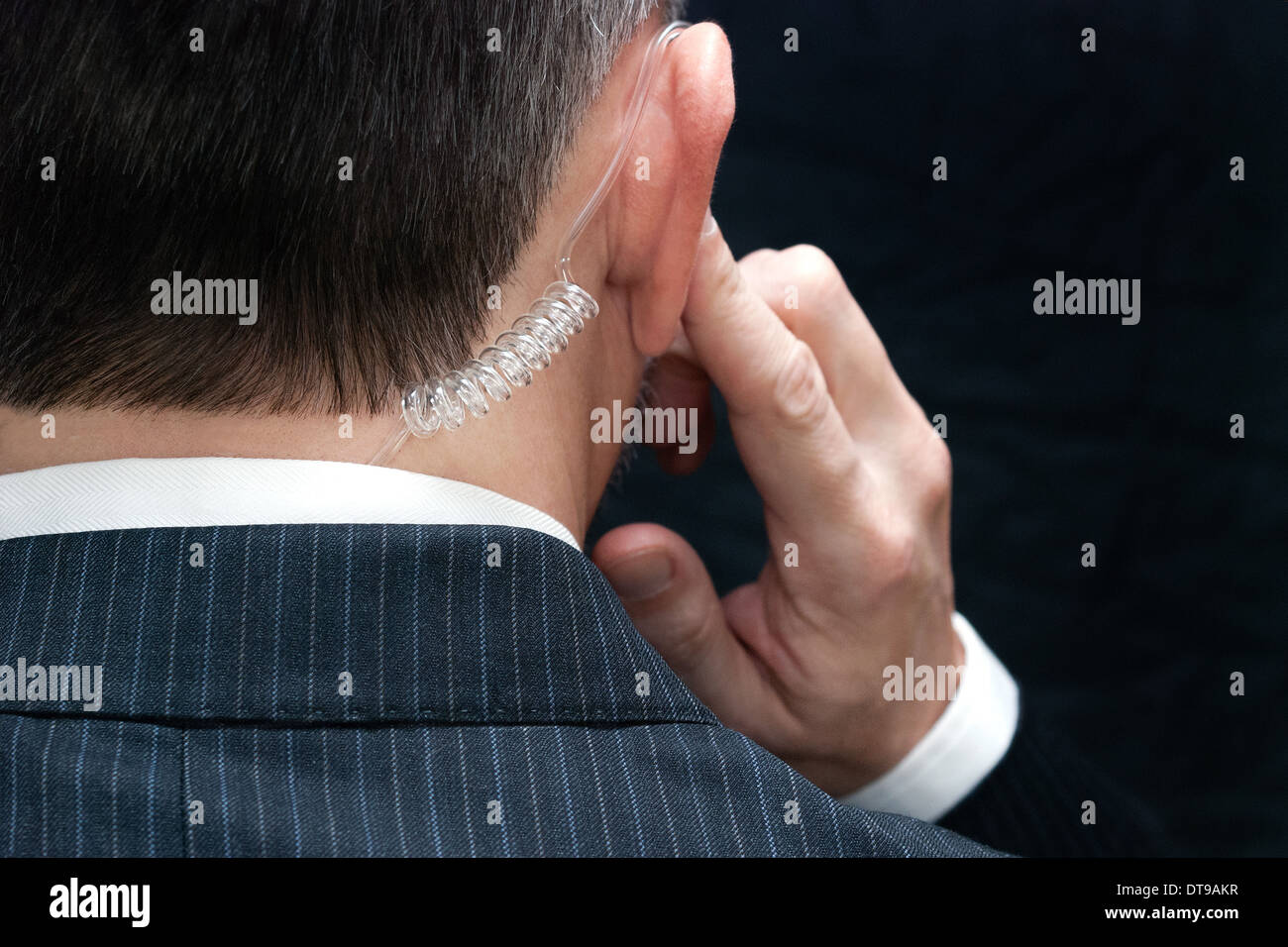 Close-up d'un agent des services secrets à l'écoute de son écouteur, derrière. Banque D'Images