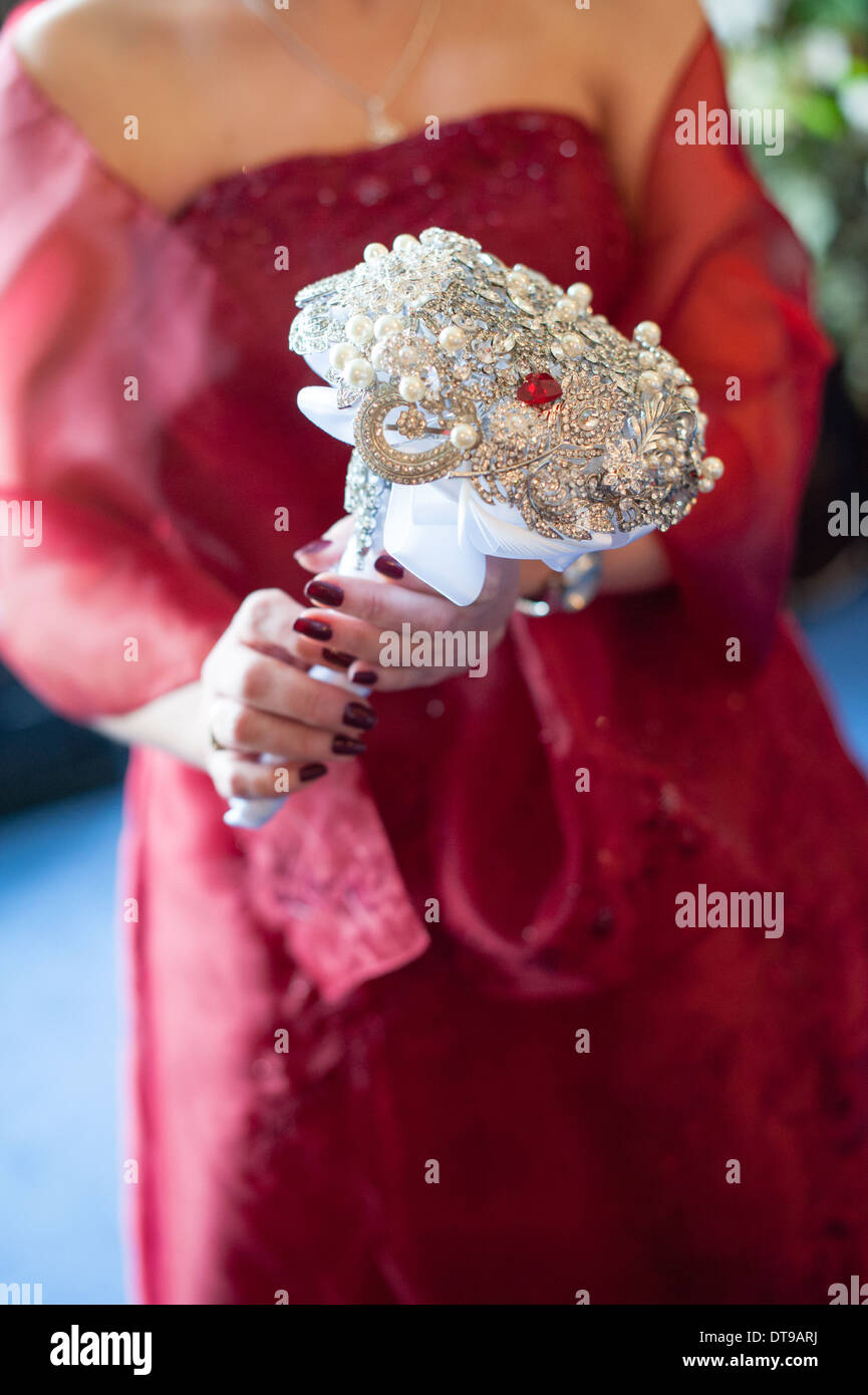 Promise dans une robe de mariage rouge est titulaire d'une alternative et ornementé mariage bouquet fait de perles, bijoux, pierres précieuses et un cœur rouge Banque D'Images