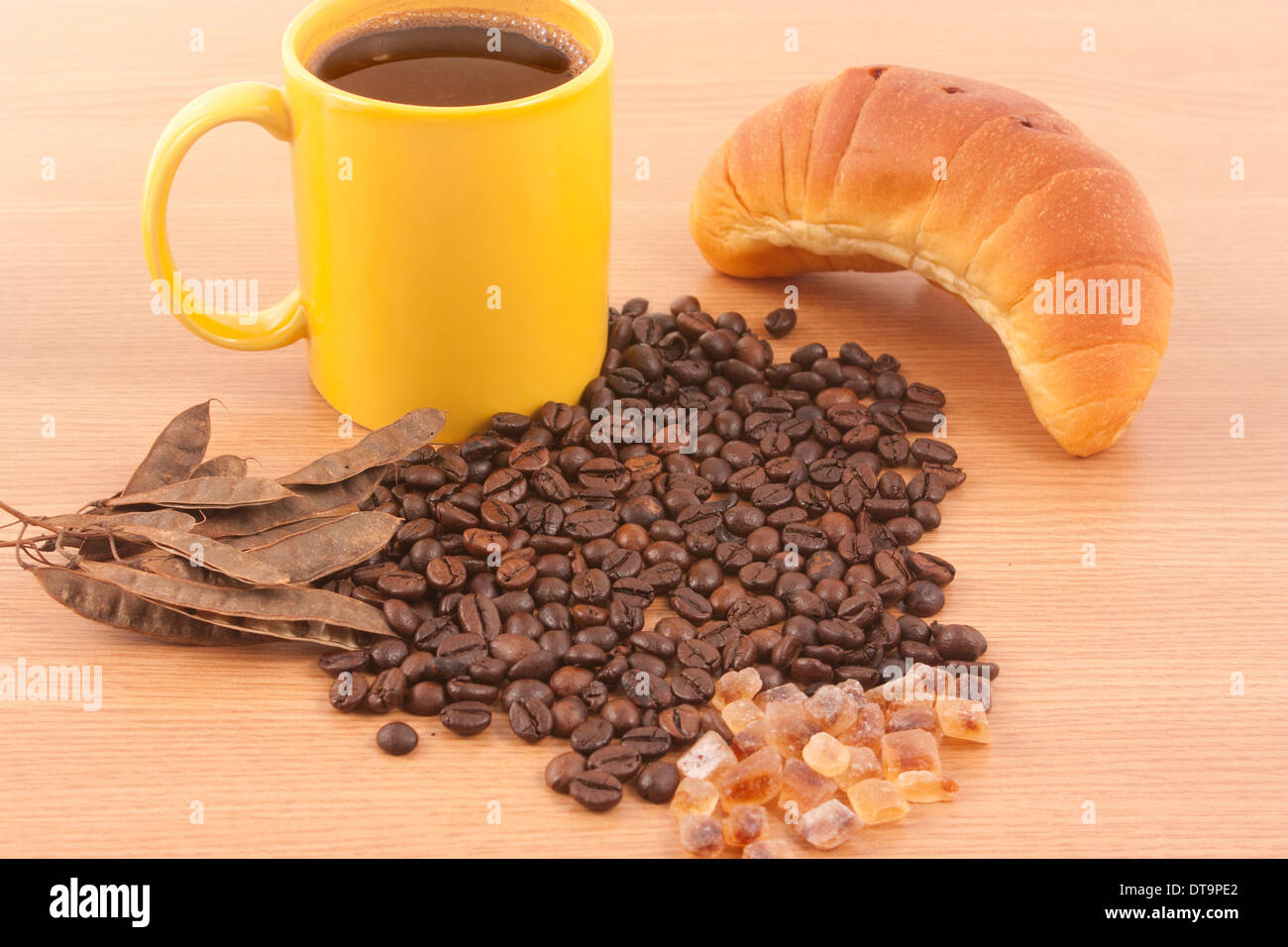 Tasse de café, le sucre brun, les grains de café et un croissant sur fond de bois Banque D'Images