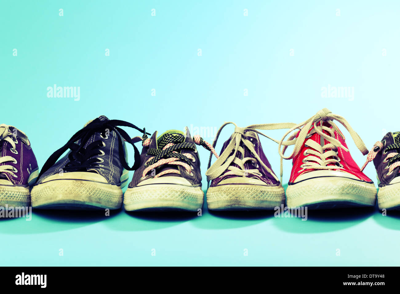 Un line-up de Converse chaussures de différentes tailles et couleurs tourné sur un fond bleu. Les traités. Studio shot. Banque D'Images