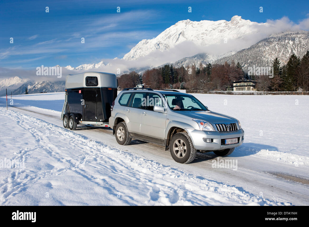 Quatre roues motrices véhicule tractant une remorque pour cheval sur une route couverte de neige dans les montagnes du Nord, Gnadenwald, Tyrol, Autriche Banque D'Images