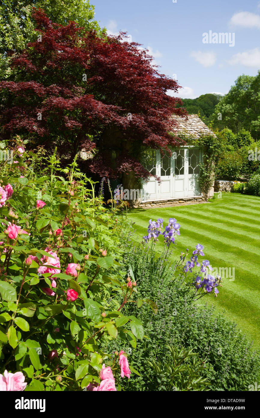 UK gardens. Parterre de pelouse à rayures d'été et une période summerhouse. Banque D'Images