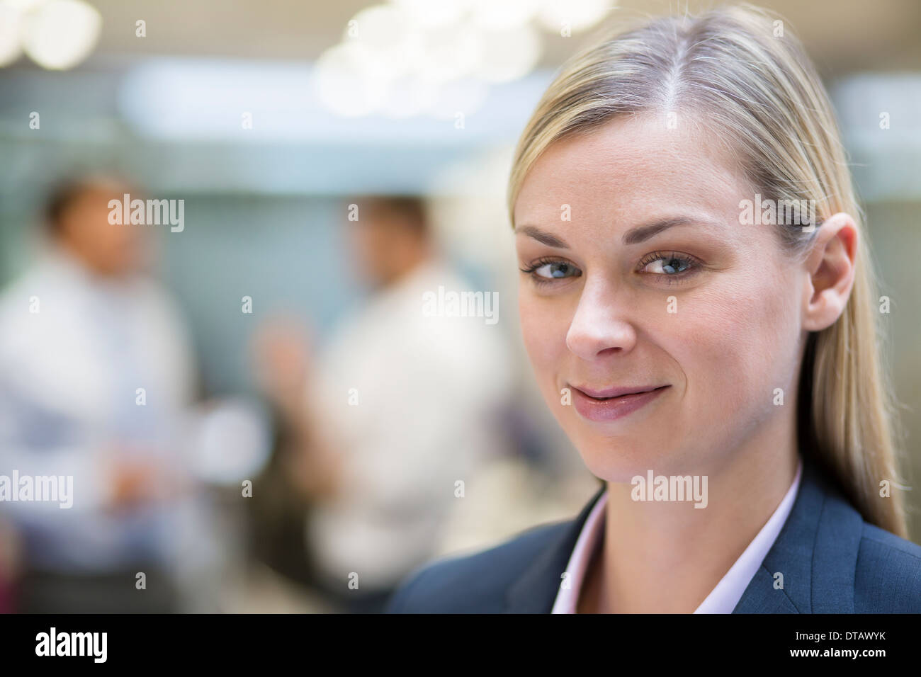 Pretty Businesswoman posing while colleagues talking together in office, à huis clos Banque D'Images