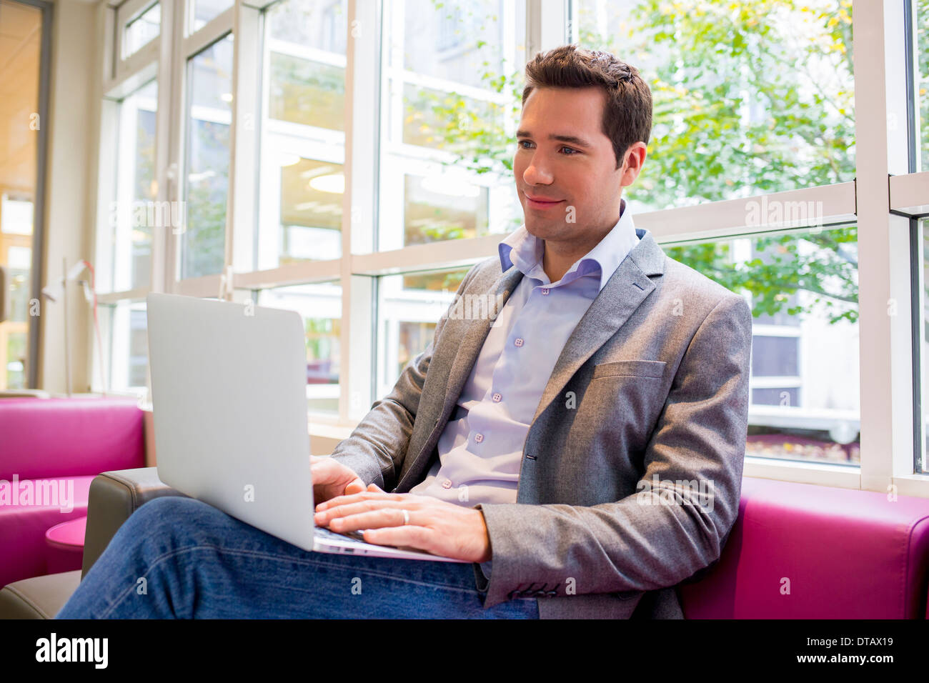 Handsome Young man with Laptop on sofa in office Banque D'Images