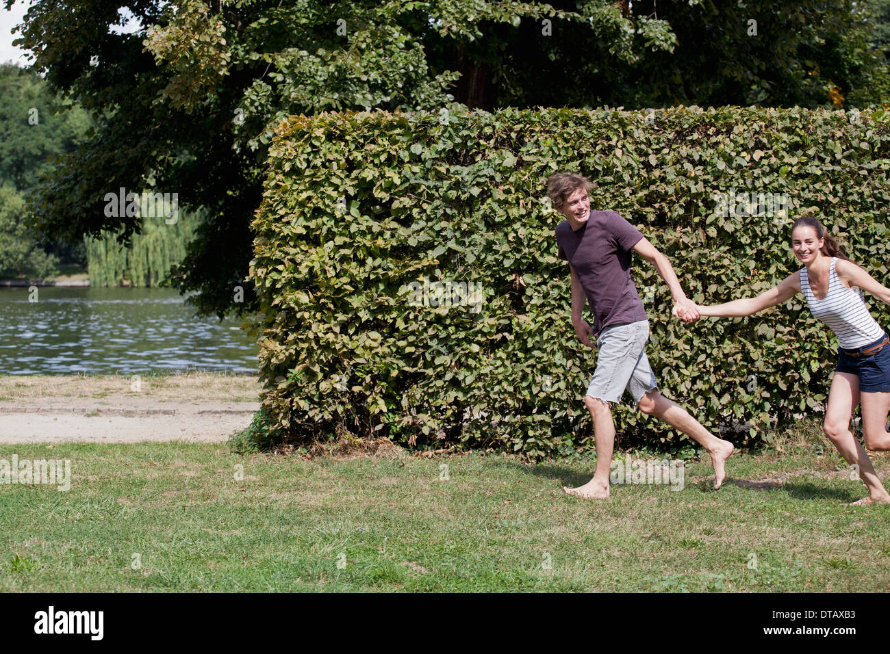 Young couple holding hands and running in park Banque D'Images