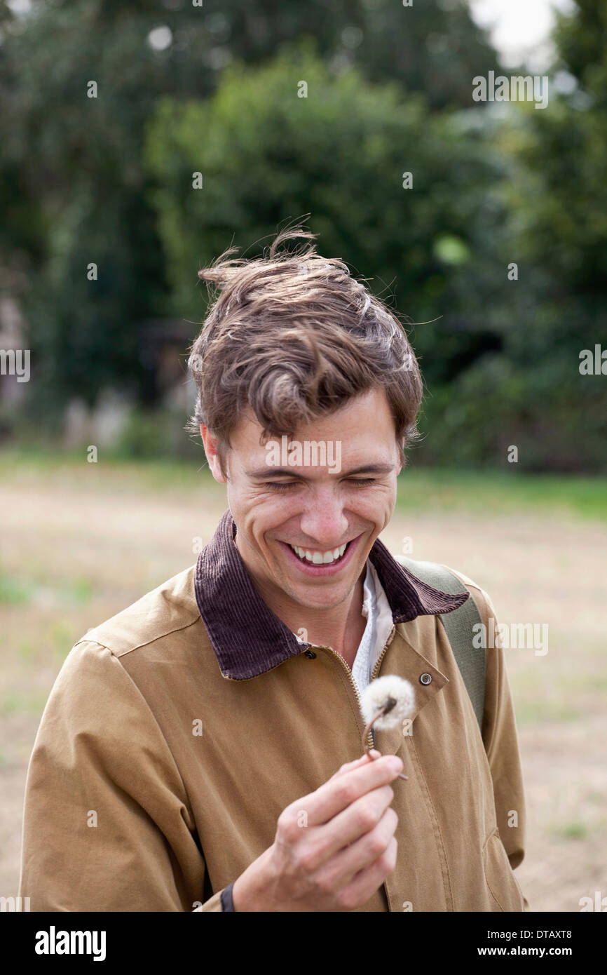 Man holding dandelion flower, smiling Banque D'Images