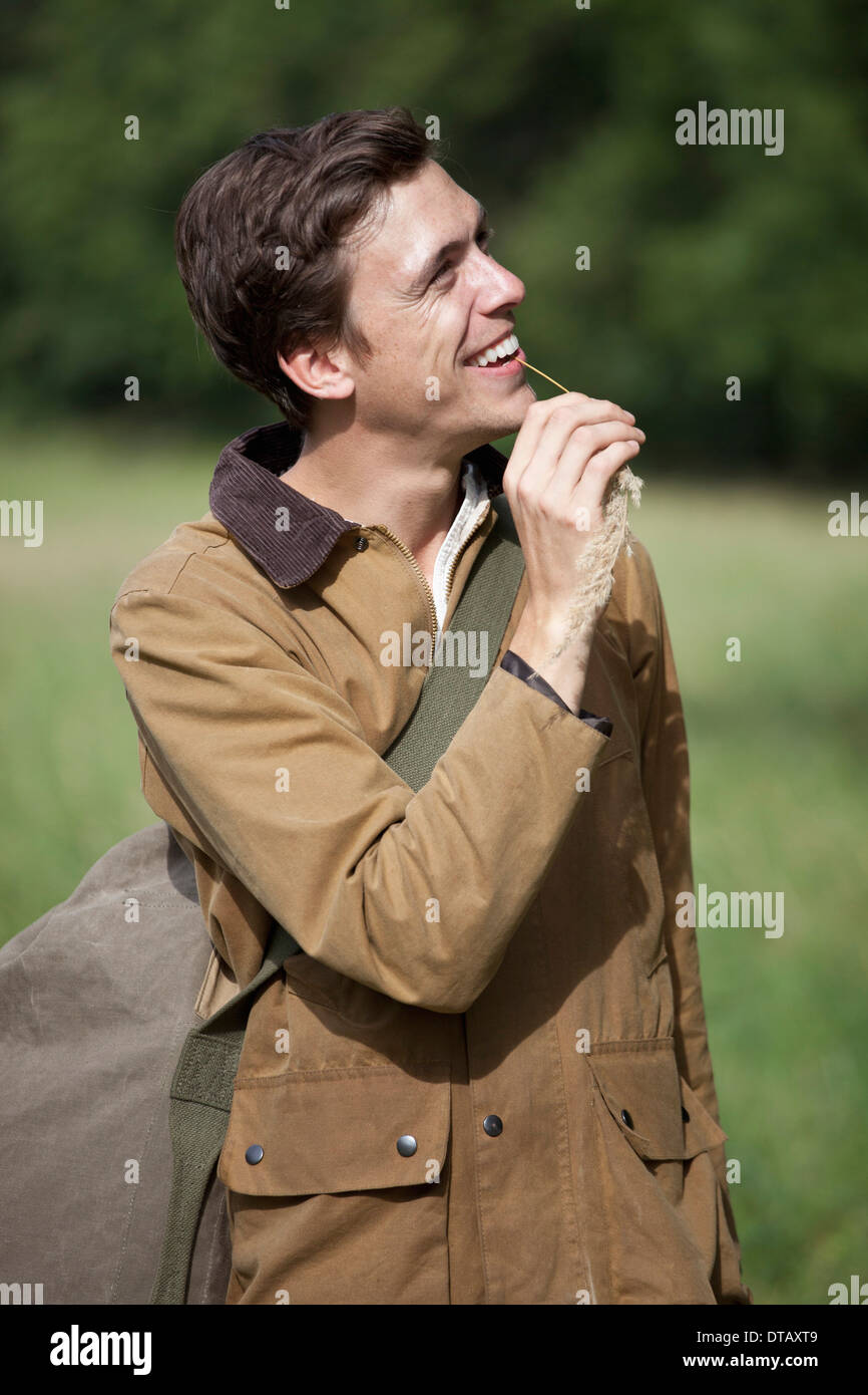 Man holding grass stalk, rire Banque D'Images