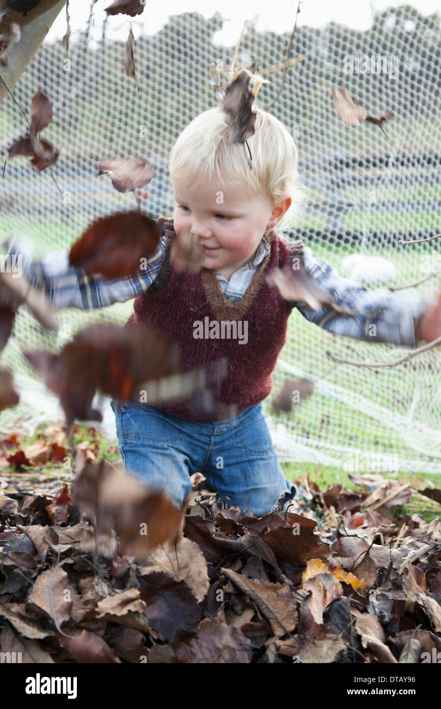 Bébé garçon en train de lancer des feuilles sèches Banque D'Images