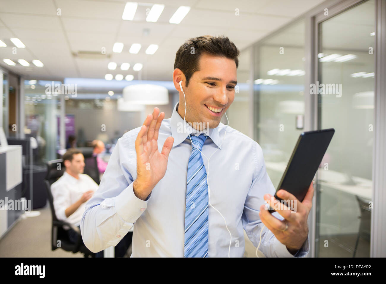 Smiling Businessman chatter sur internet avec Tablet PC, l'arrière-plan de bureau Banque D'Images