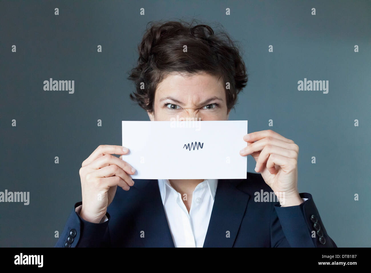 Portrait of mid adult woman holding paper avec signe en zigzag, close-up Banque D'Images