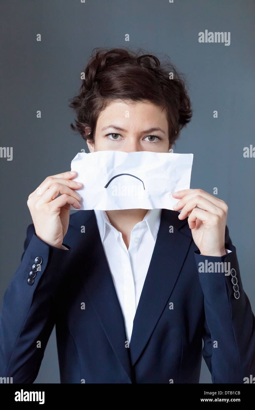 Portrait of mid adult woman holding paper avec froncement, close-up Banque D'Images