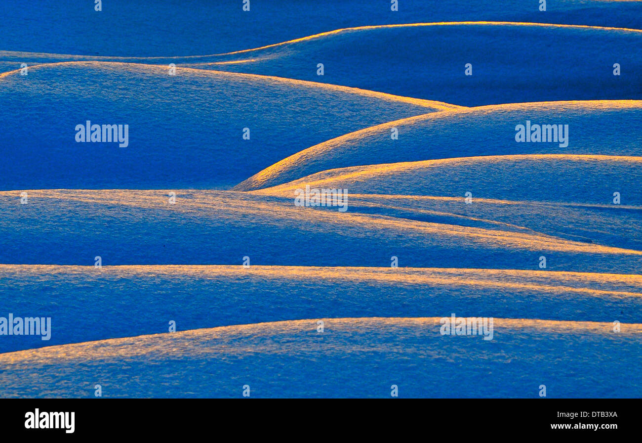 Un paysage hivernal d'une série de lignes d'or créée par le soleil qui se reflète sur le sommet de collines couvertes de neige Banque D'Images