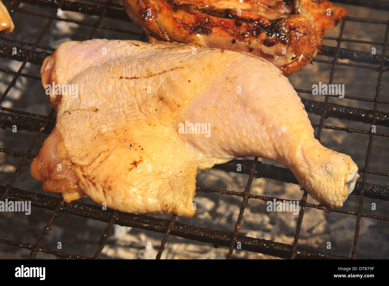 Cuisse de poulet grillé sur le grill en flammes Banque D'Images