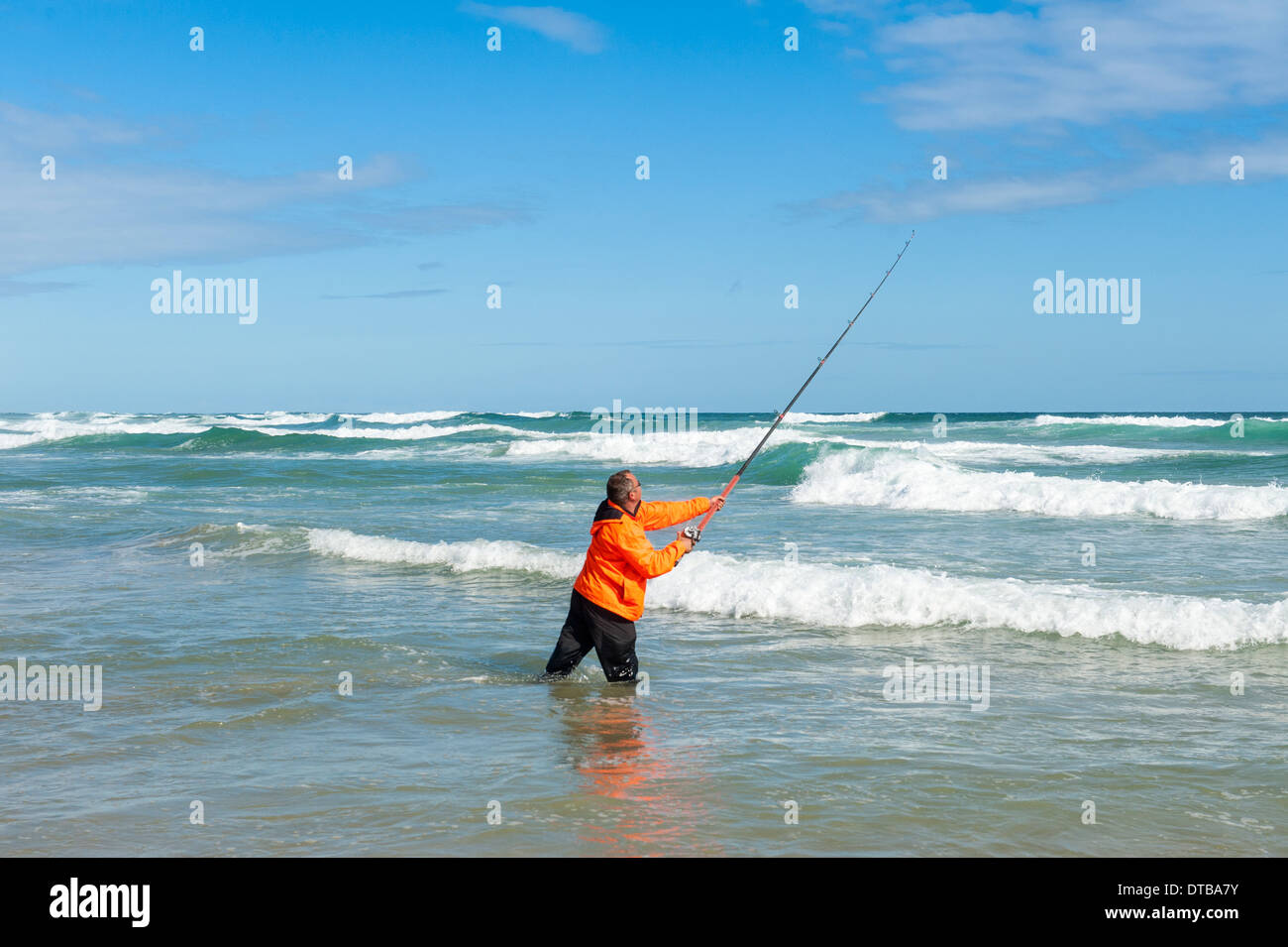 Fisherman casting une canne à pêche debout dans les vagues déferlantes, Sedgefield, Eastern Cape, Afrique du Sud Banque D'Images