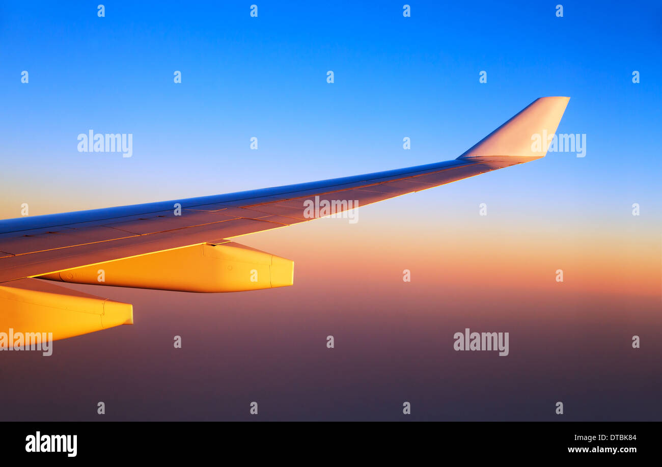 Des ailes d'avion dans le coucher du soleil, la lumière orange vif soleil de luxe, transport aérien, voyage d'affaires, voyages et tourisme concept Banque D'Images