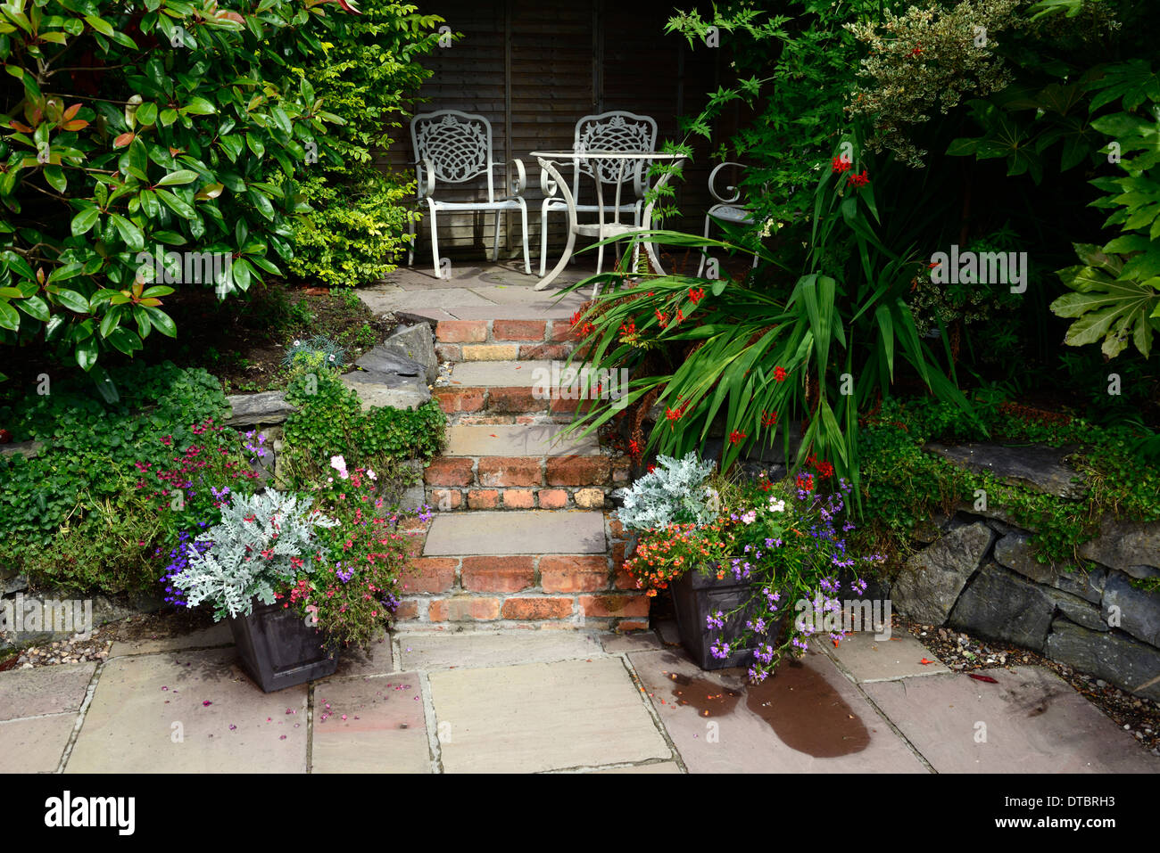 Coin salon patio surélevé étapes de brique rouge conteneur conteneur en fer forgé blanc jardinage sièges siège régime plantation mixte Banque D'Images