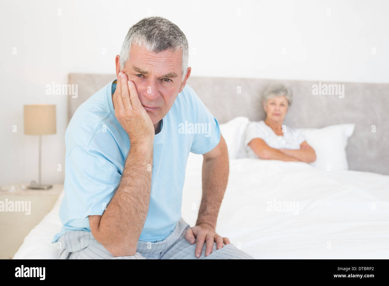 Sad senior man with woman in bed Banque D'Images