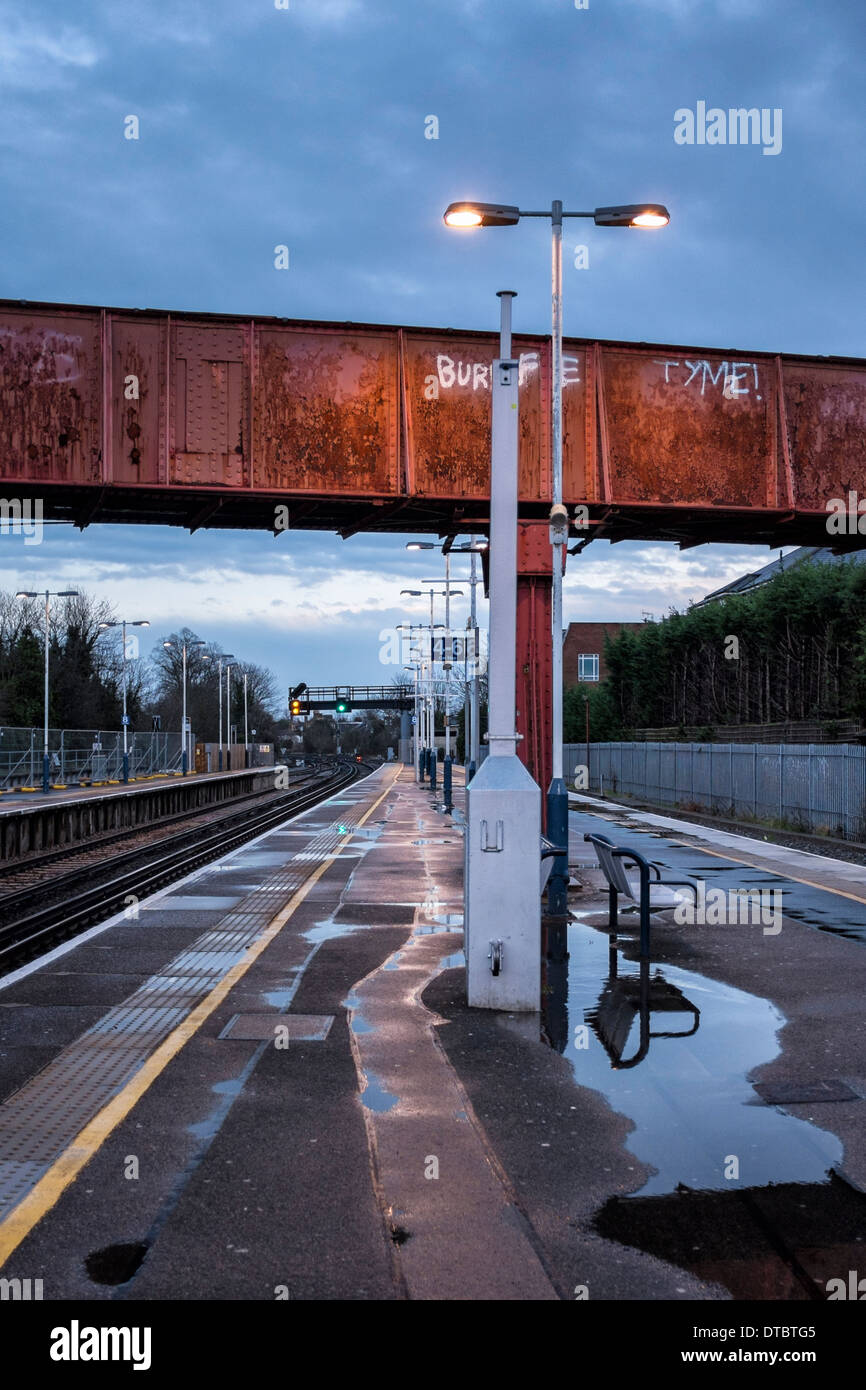La plate-forme de la gare de Twickenham déserte tôt le matin avec les postes, les piscines d'eau de pluie et passage supérieur, London, UK Banque D'Images