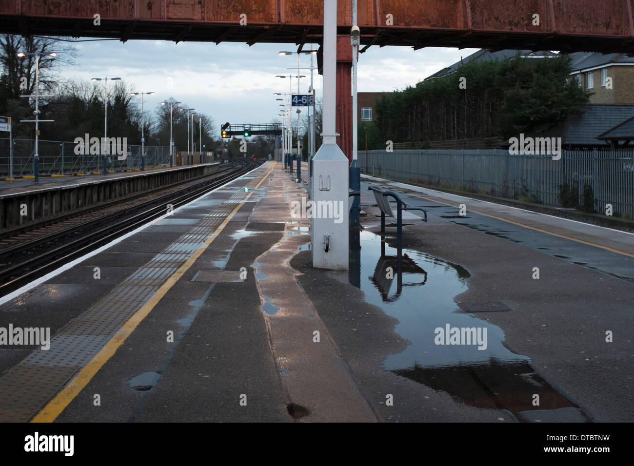 La plate-forme de la gare de Twickenham déserte tôt le matin avec les postes, les piscines d'eau de pluie et passage supérieur, London, UK Banque D'Images