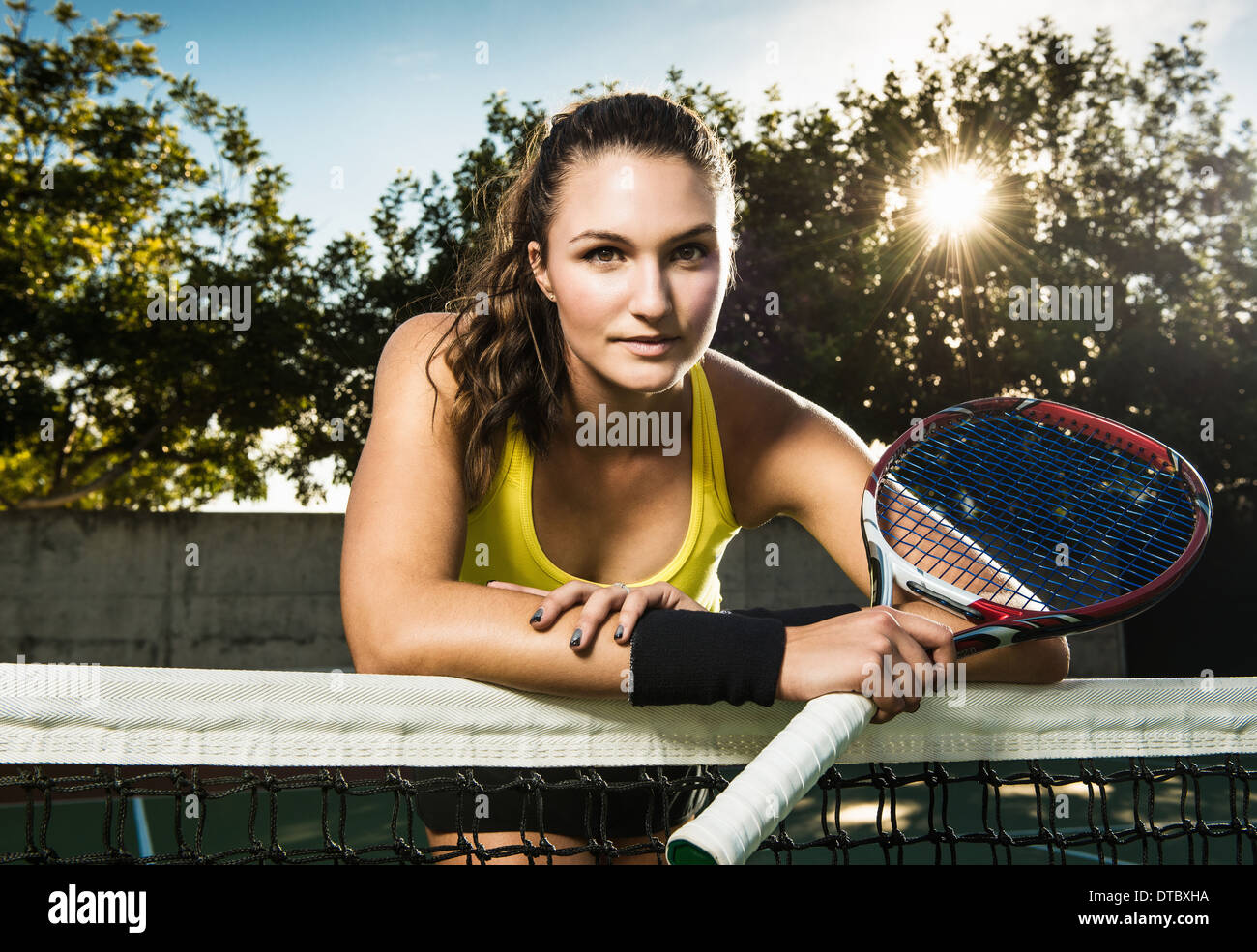 Tennis player holding racket leaning on net Banque D'Images