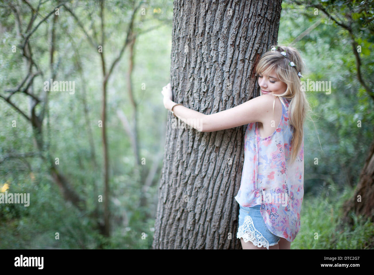 Teenage girl hugging tree à woodland Banque D'Images