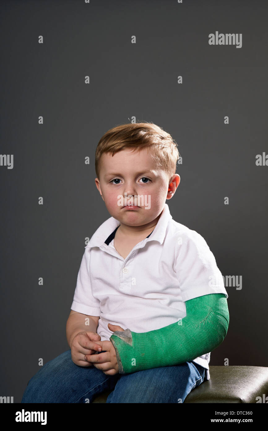 Portrait de jeune garçon maussade avec plâtre sur bras Banque D'Images