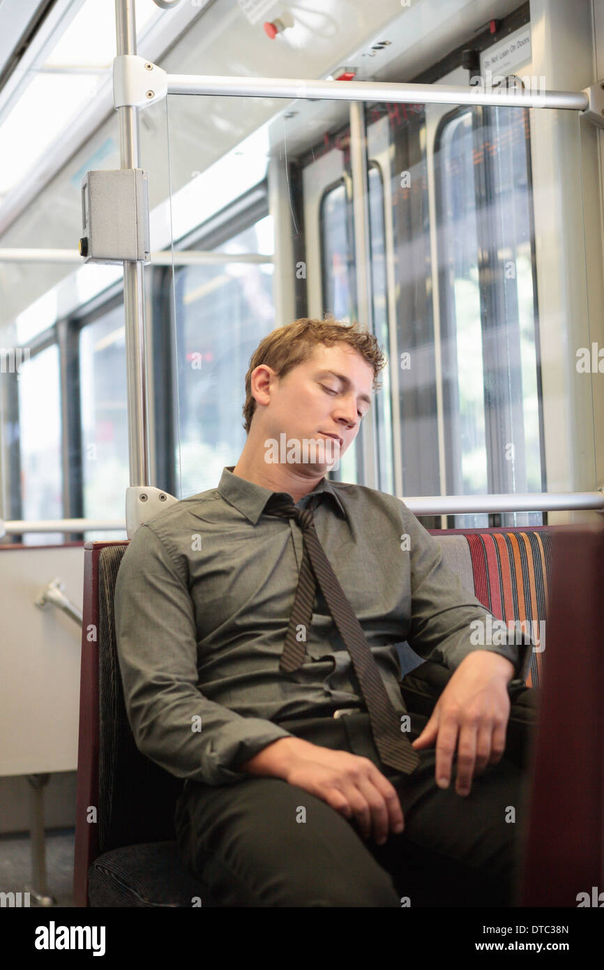 Young office worker snoozing sur voyage en train Banque D'Images