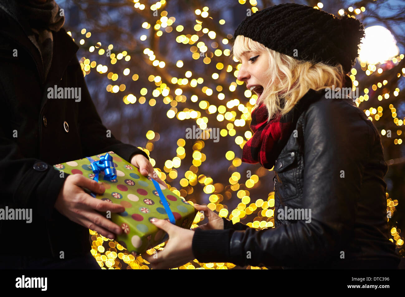 Young woman receiving xmas gift on city street Banque D'Images