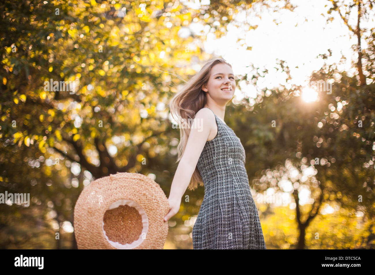 Teenage girl holding chapeau running in park Banque D'Images
