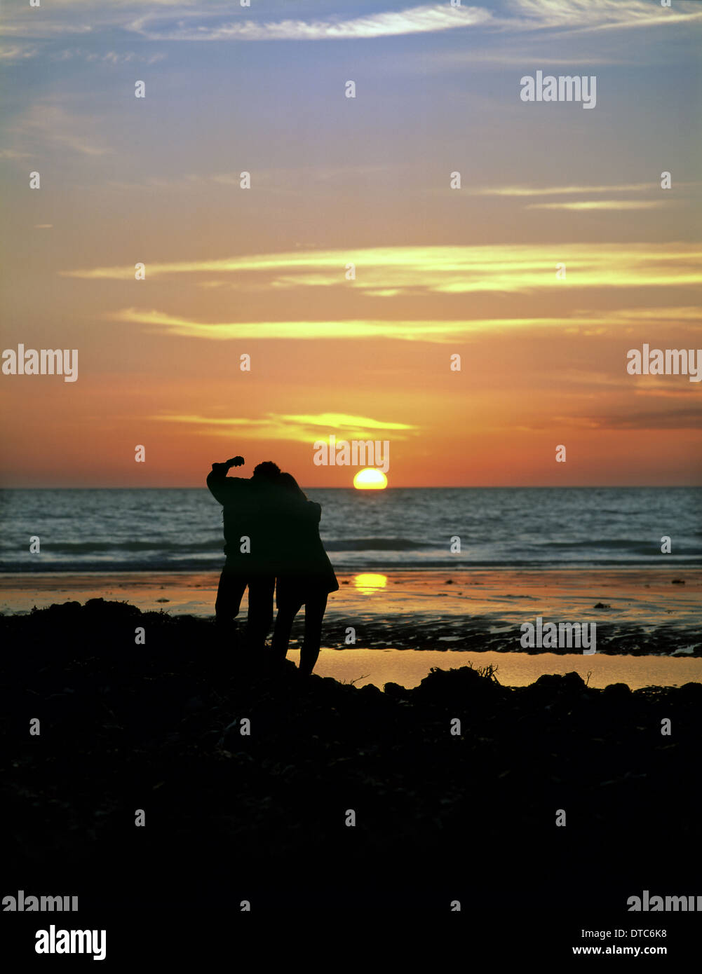 Couple watching un coucher de soleil sur la côte à Urrugne dans les South Downs National Park, East Sussex. Banque D'Images