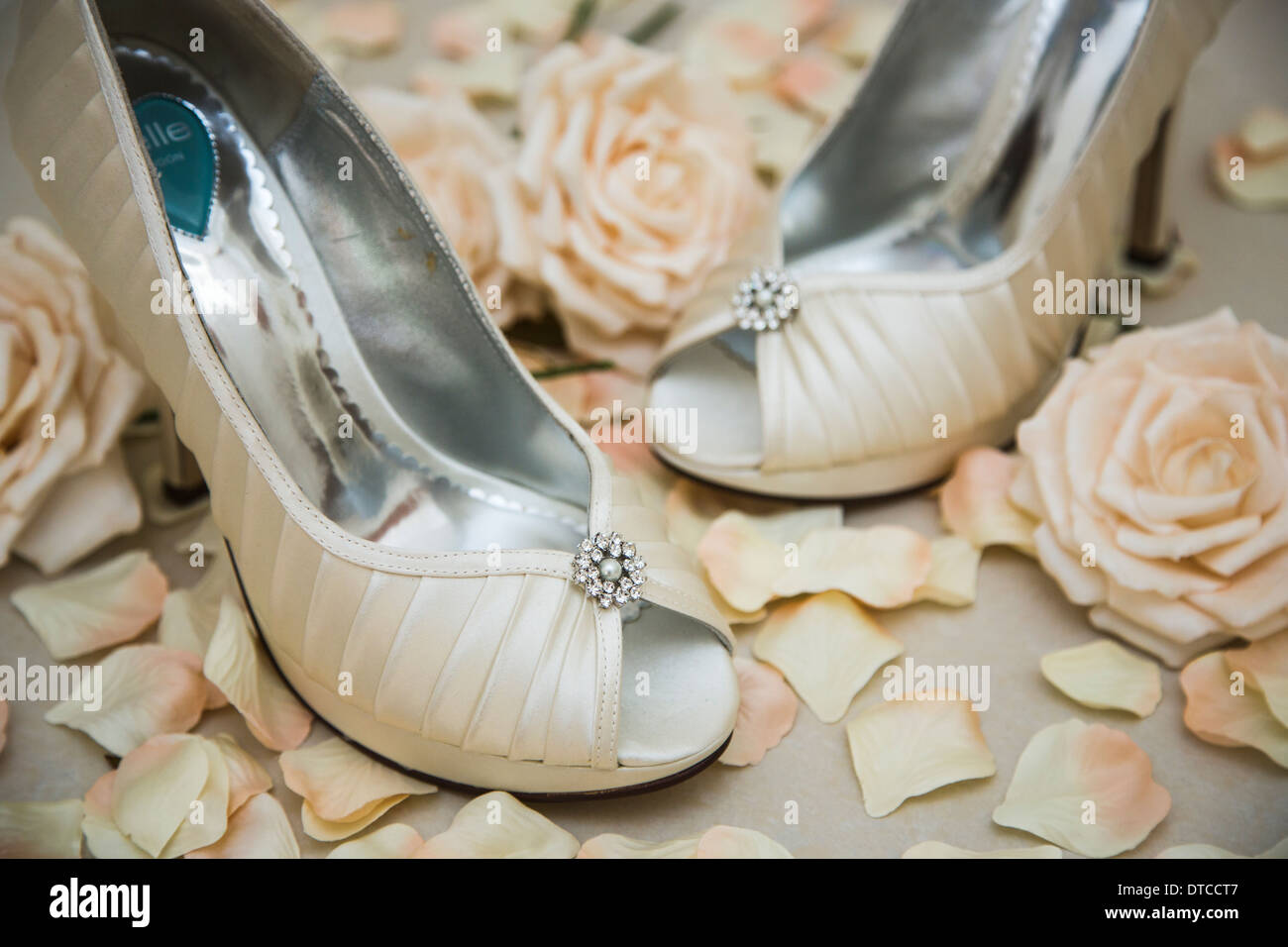 Satin blanc élégantes chaussures à talons hauts avec effet diamant sparky décoration pour une fiancée, avec des fleurs et des pétales de rose Banque D'Images
