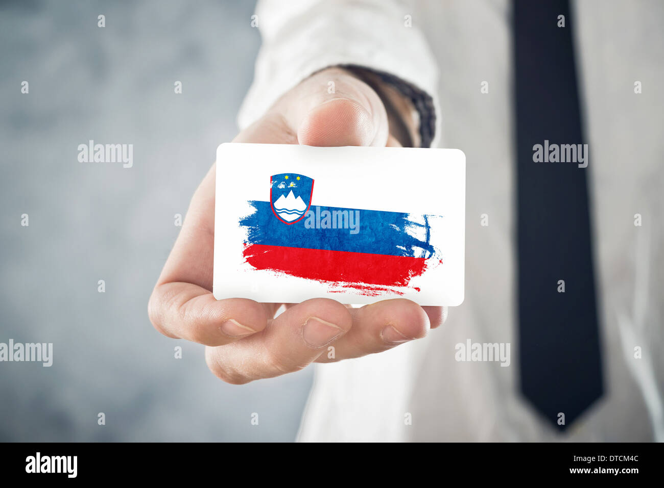 Businessman holding slovène carte d'affaires avec la Slovénie Drapeau. La coopération internationale, les investissements, les occasions d'affaires Banque D'Images