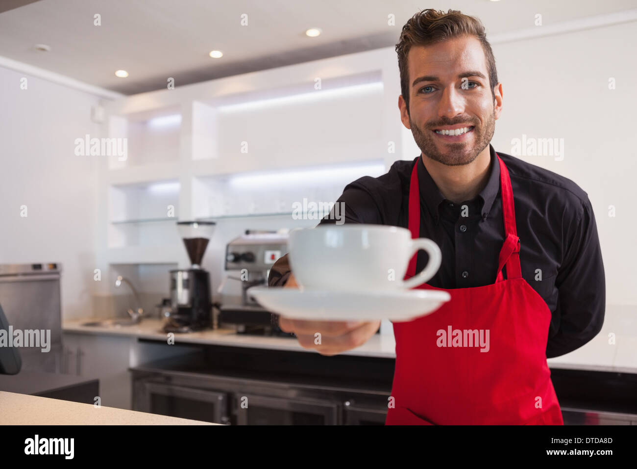 Barista heureux offrant une tasse de café à l'appareil photo Banque D'Images