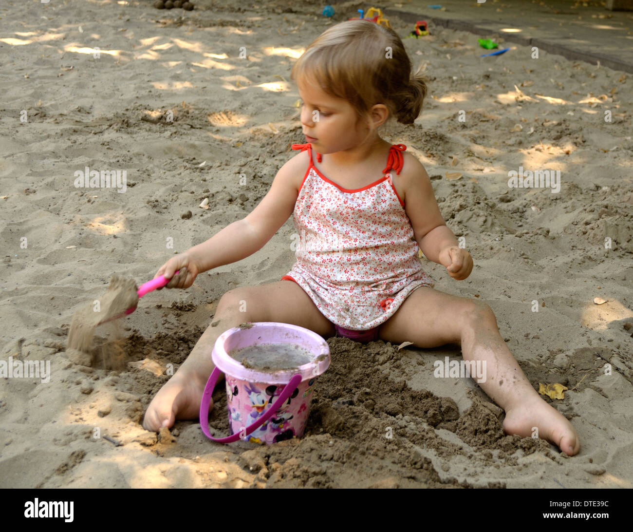 Fillette de trois ans jouant dans un bac à sable Banque D'Images