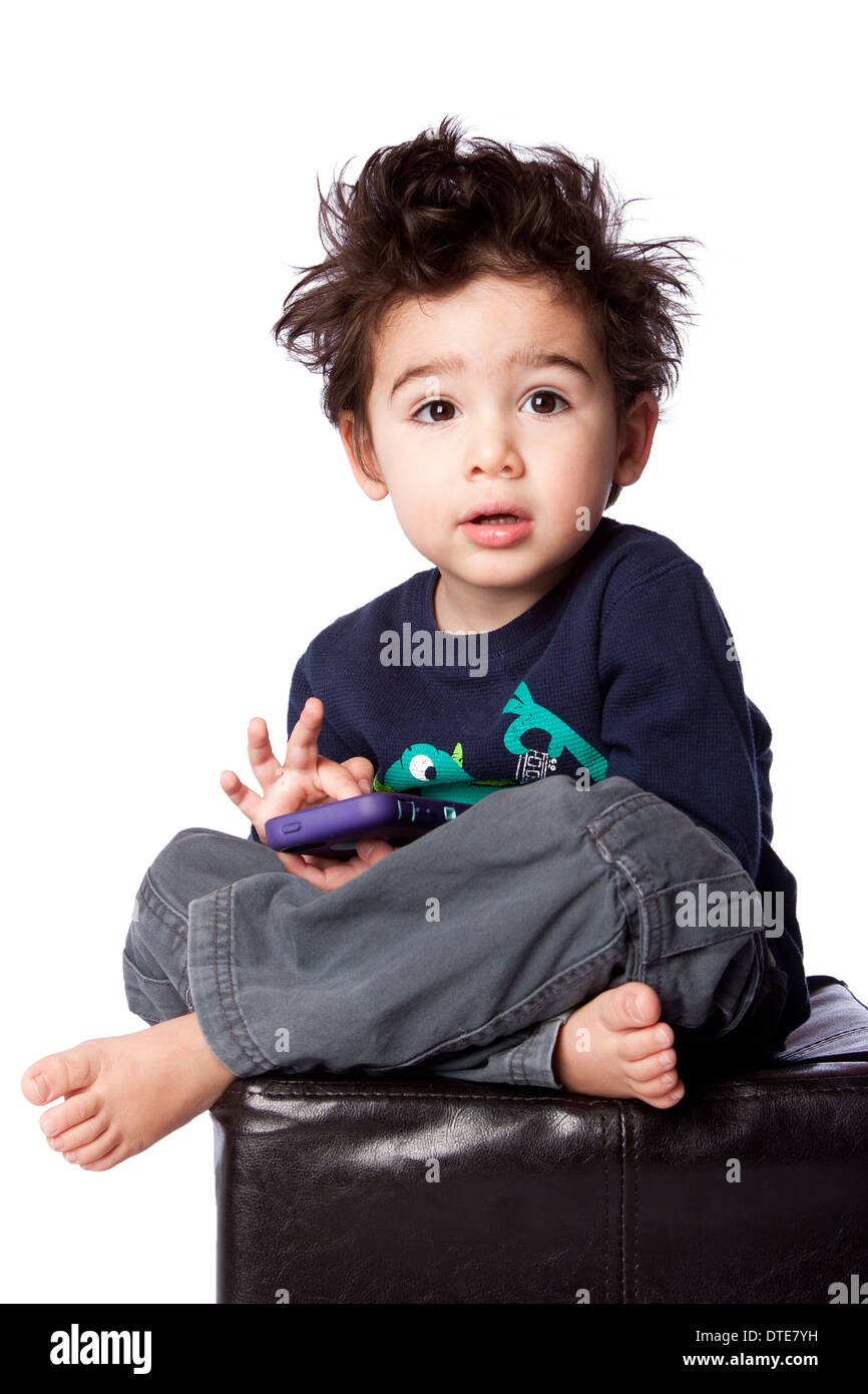 Mignon bébé garçon assis avec l'appareil mobile et les cheveux fous, isolé. Banque D'Images