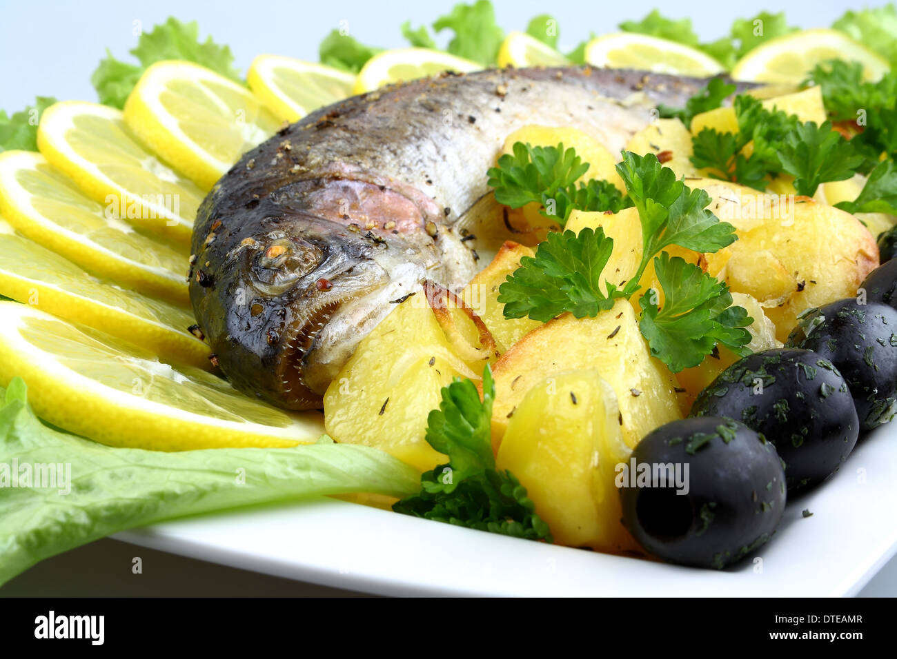 Truite grillée avec des pommes de terre, salade, olives noires, citron, Close up Banque D'Images