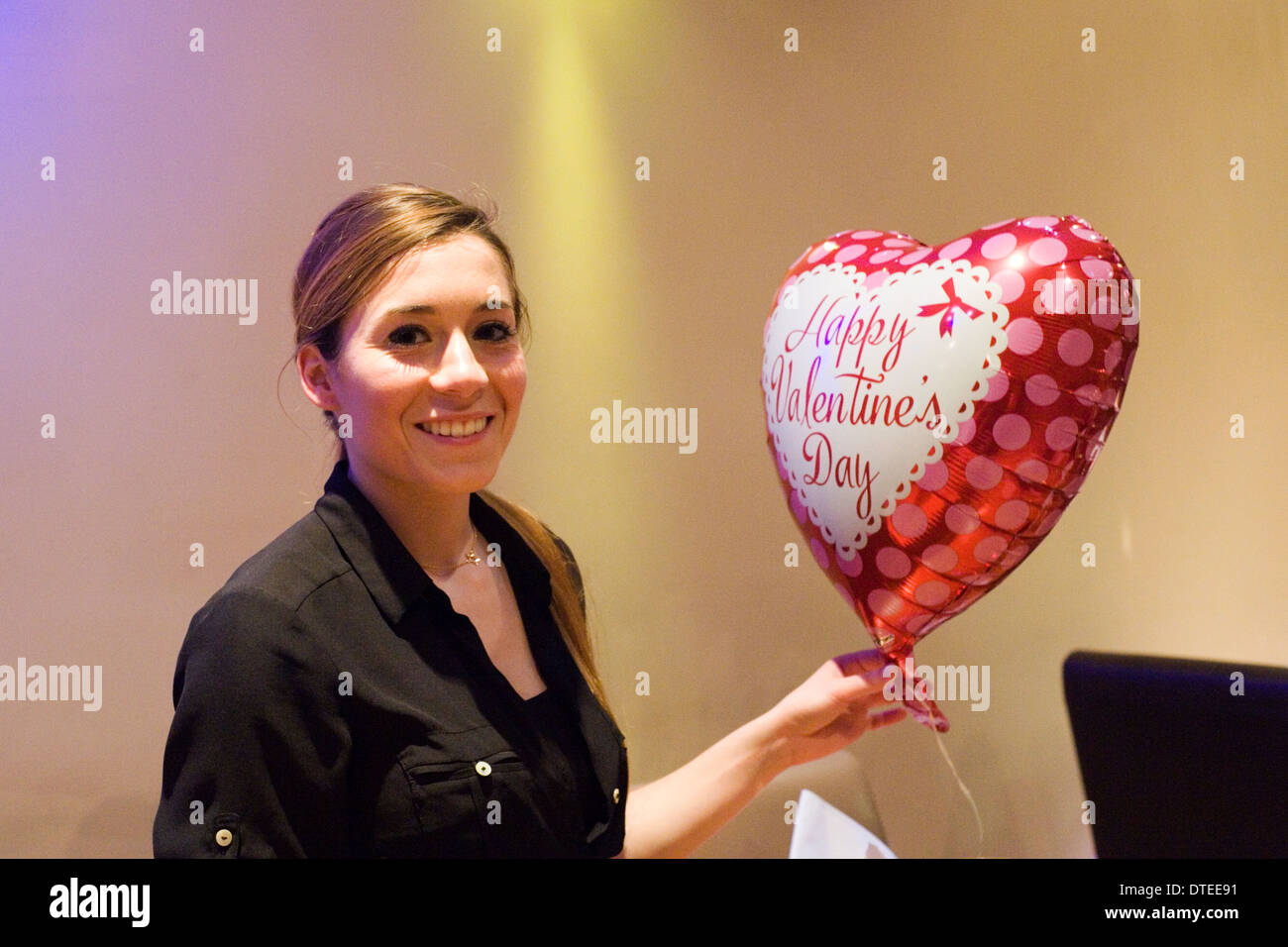 Jeune femme avec ballon en forme de coeur saint Valentin romantique bénéficiant d''un emplacement calme dans un restaurant de nuit Banque D'Images