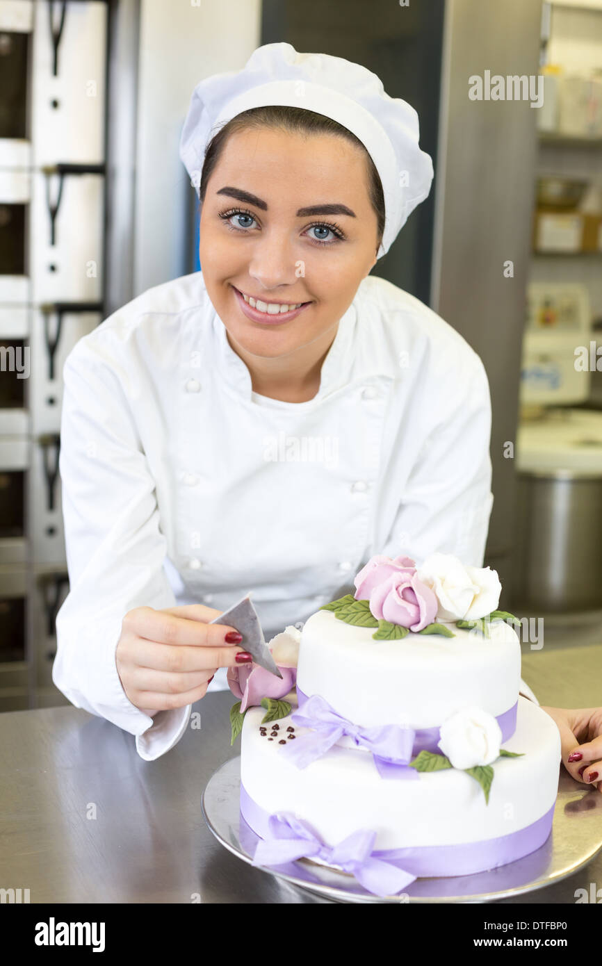 Boulanger ou pâtissier écrit quelque chose sur un gâteau avec du colorant alimentaire Banque D'Images