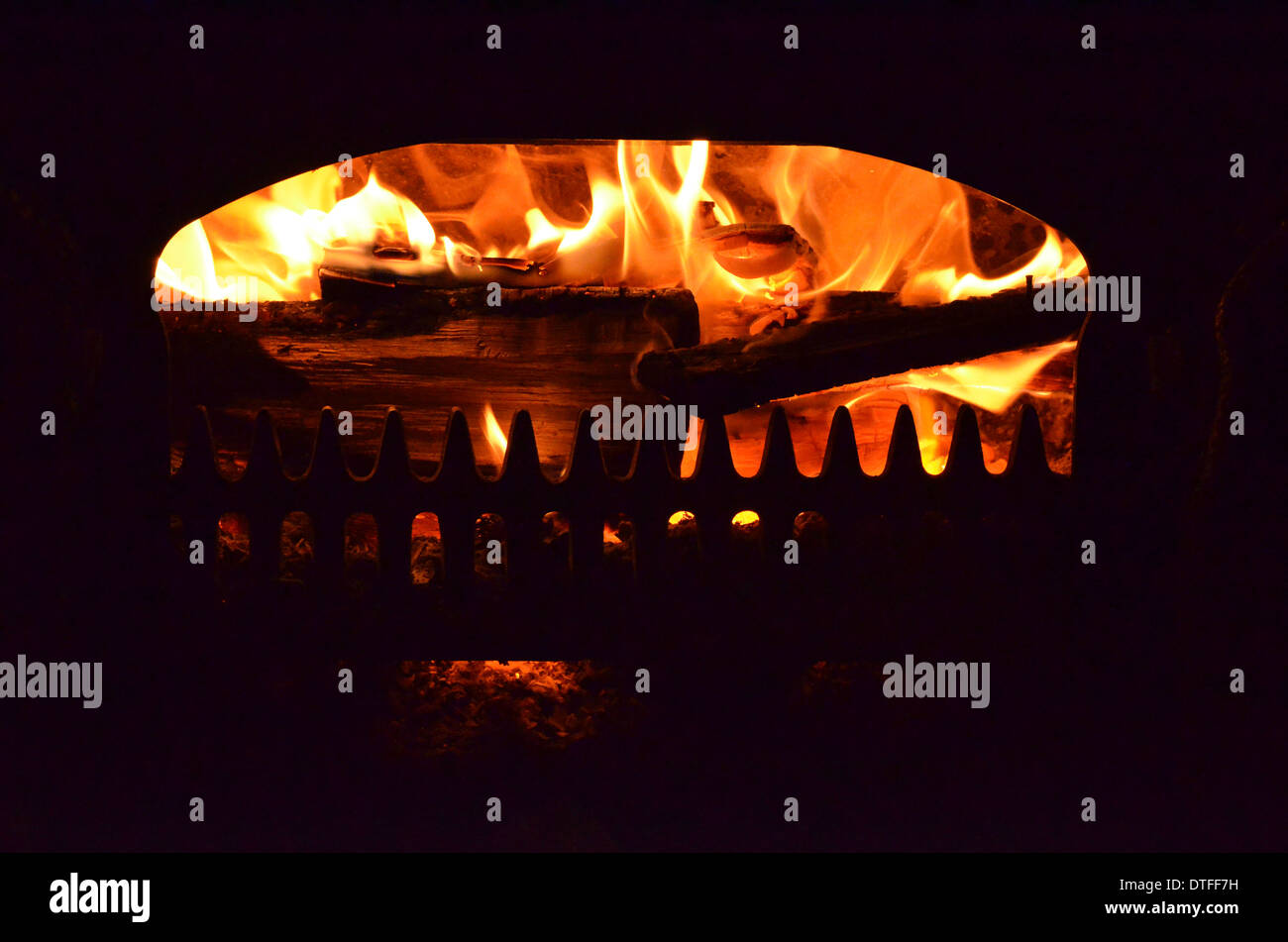 Vu du feu qui brûle dans la grille ouverte d'un poêle à bois. "En flammes" métaphore peut-être. Banque D'Images