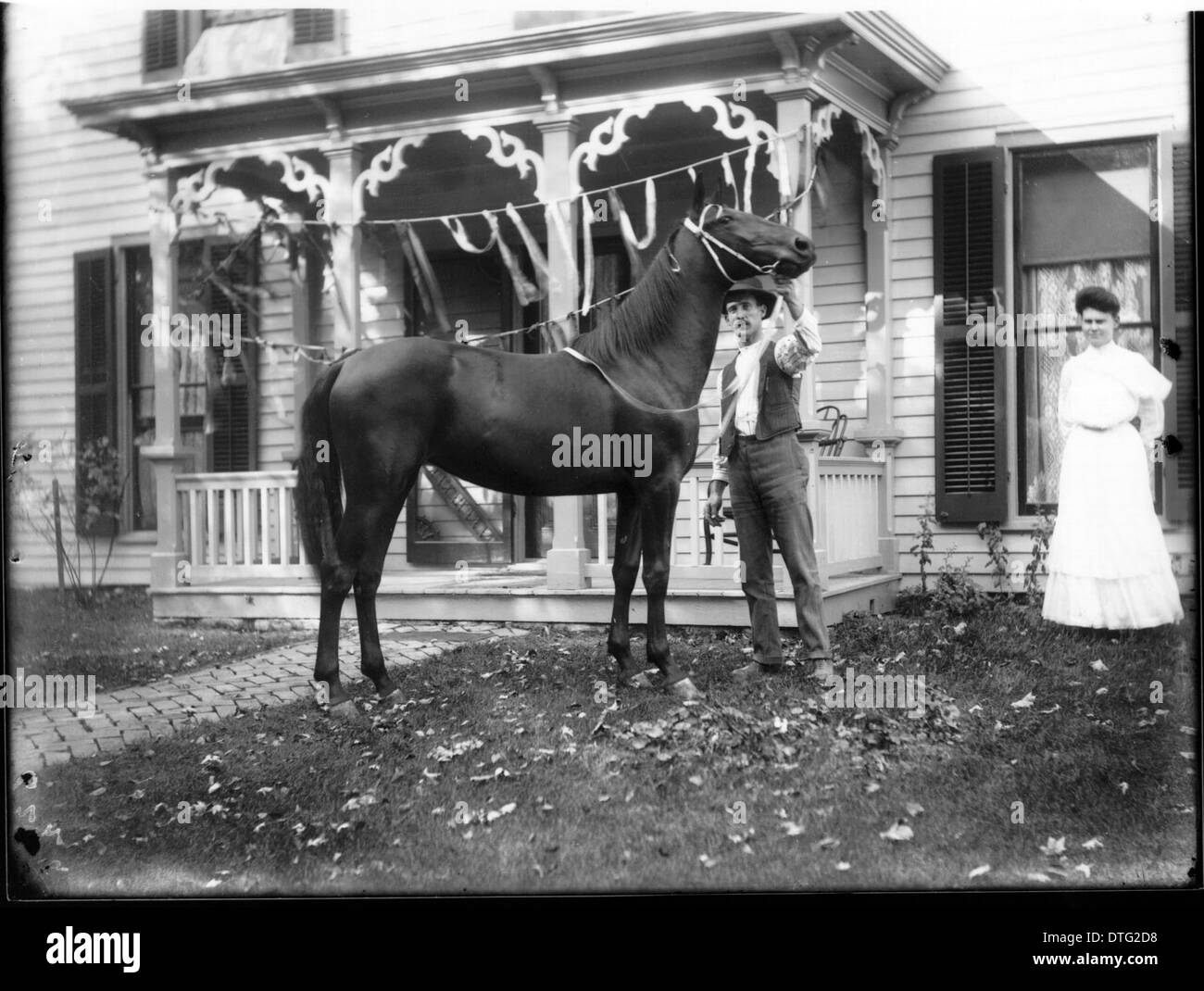 Cette photographie de 1904 capture une scène rurale représentant un homme, une femme et un cheval debout devant une ferme, représentant la vie agricole de l'Amérique du début du XXe siècle. L'image met en évidence la vie rurale et l'élevage pendant cette période. Banque D'Images