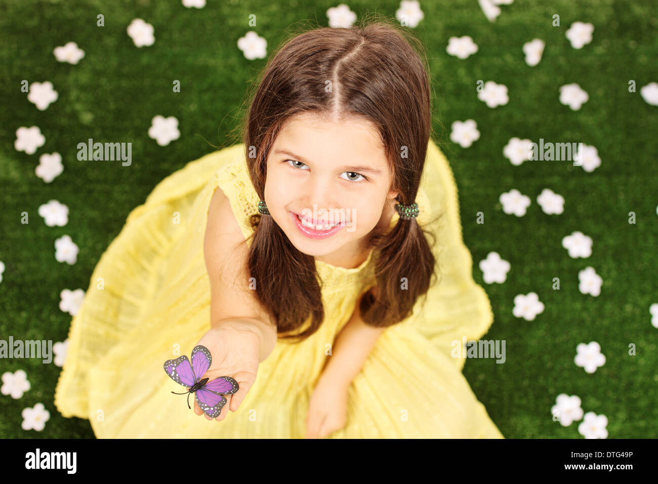 Little girl holding un papillon dans un champ plein de fleurs Banque D'Images