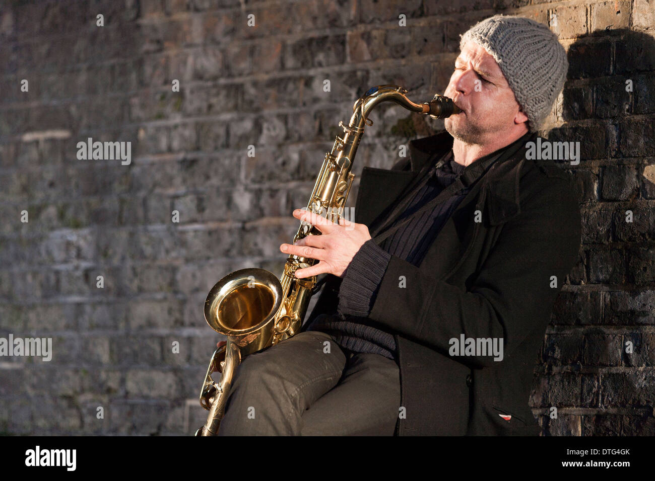 Musicien ambulant de la rue / street player / saxophoniste jouant du saxophone dans le cadre de la brique arch à Twickenham, Londres. UK. Banque D'Images