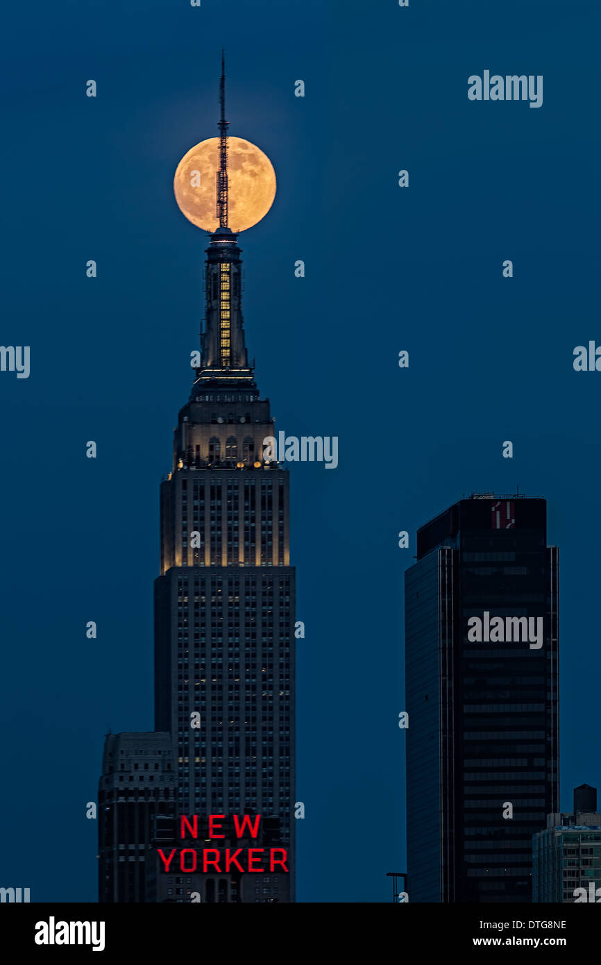 La super pleine lune se lève sur l'Empire State Building à New York pendant l'heure bleue après le coucher du soleil. Banque D'Images