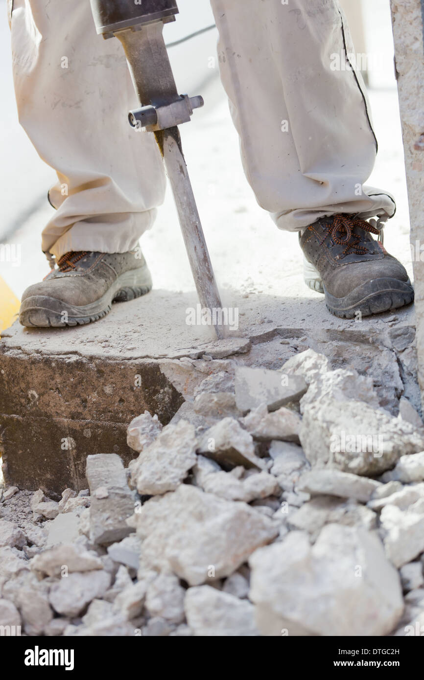 Démolition du travailleur en béton avec un marteau perforateur. Banque D'Images