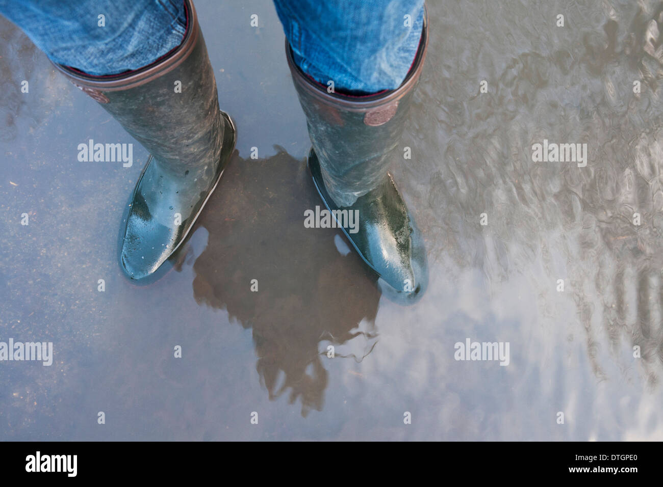 En regardant un les jambes portant des bottes wellington Wellies (Permanent) dans l'eau d'inondation. Banque D'Images