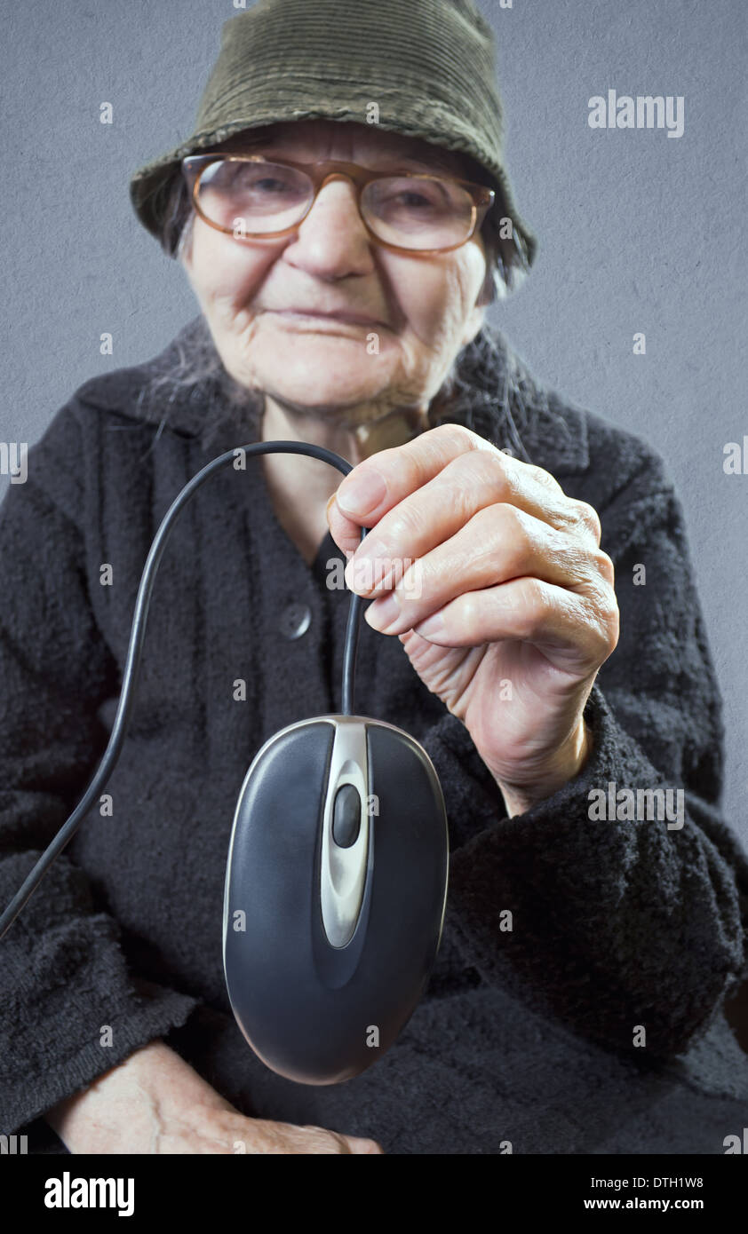Vieille Femme tenant une souris d'ordinateur. Selective focus om souris d'ordinateur. Banque D'Images
