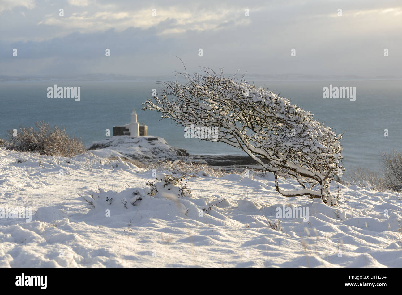 Vêtu de neige phare avec Bush en arrière-plan avec vue sur le phare de Mumbles, Bracelet Bay, Swansea, Wales, UK Banque D'Images