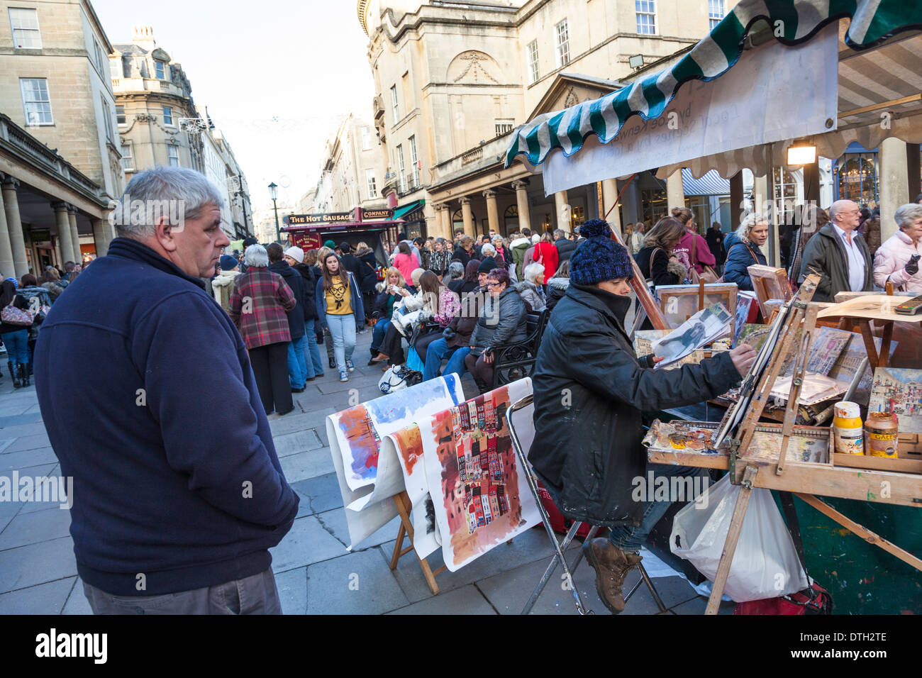 Les peintures d'un artiste à son étal dans le marché de Noël allemand dans la baignoire comme un passant par les regarde. Banque D'Images