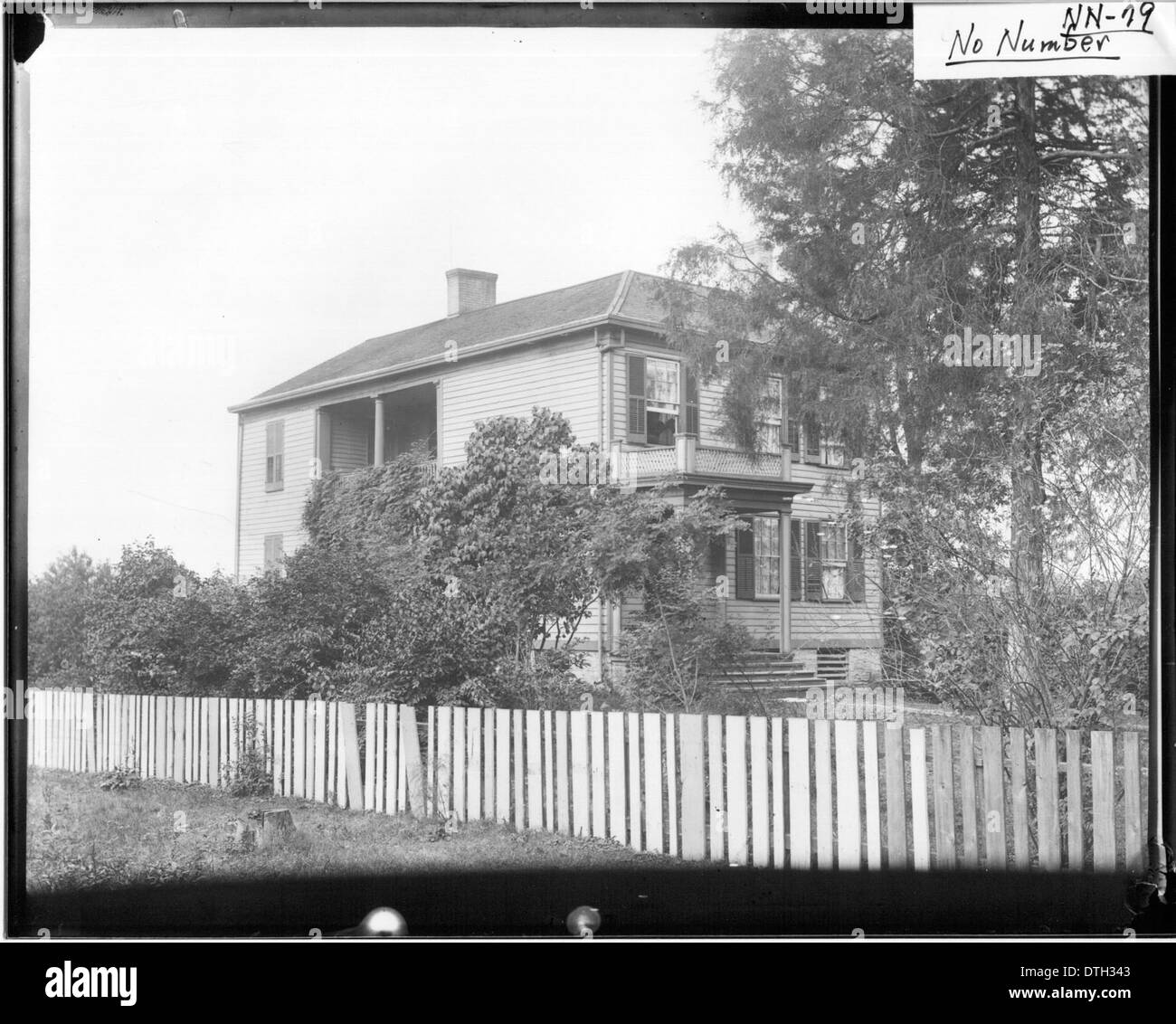 Cette photographie capture une maison de deux étages avec une clôture, mettant en valeur l'architecture résidentielle du début du XXe siècle. L'image reflète le design modeste et fonctionnel des maisons de banlieue de cette époque. Banque D'Images