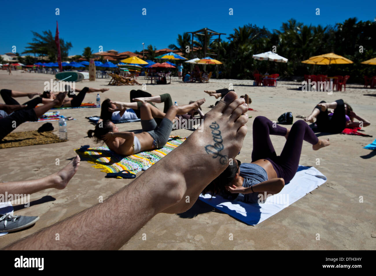 Les jeunes pratiquant le yoga à plage de Geriba, Armacao de Buzios, Rio de Janeiro, Brésil de l'État. La paix de tatouage Banque D'Images